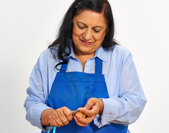 Woman standing at kitchen counter and peeling a potato