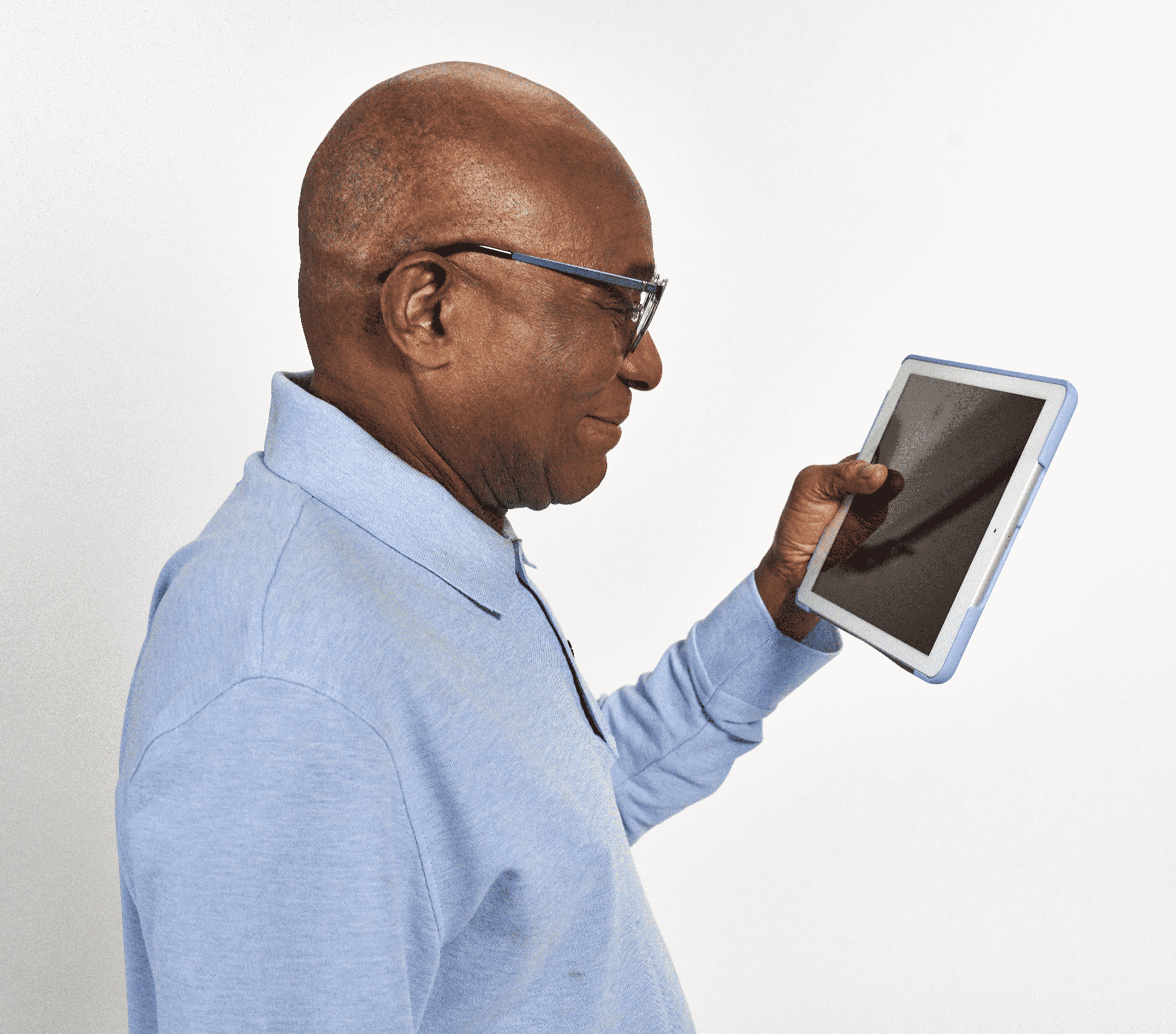 Man with glasses smiling while looking at digital tablet