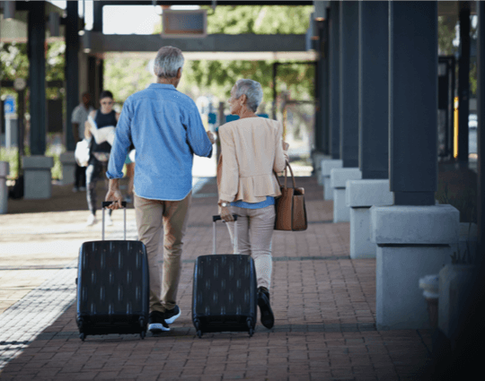 couple walking with suitcases outside of airport terminal