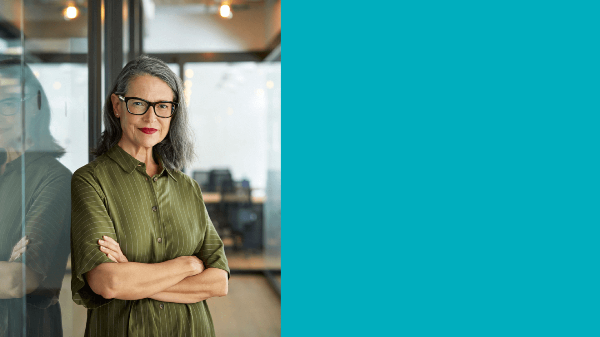 Woman wearing glasses standing in office with arms crossed and smiling